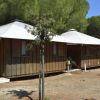 Due bungalow di legno con tetti bianchi, circondati da alberi.