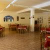 Sala pranzo con tavoli apparecchiati e sedie in legno.