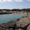 Cala rocciosa con mare cristallino e bagnanti.