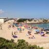 Spiaggia affollata di bagnanti e ombrelloni colorati.