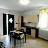 Cucina aperta con tavolo, sedie e una piccola TV. Decorazioni floreali alle finestre.