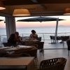Ristorante con vista sul mare al tramonto, persone sedute ai tavoli.