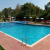 Piscina all'aperto con ombrelloni a strisce e lettini.