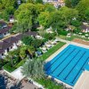 Vista aerea di piscina e bungalow tra alberi.