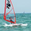 Windsurfisti al mare con vele colorate.