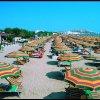 Spiaggia affollata con ombrelloni colorati.