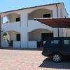Edificio bianco a due piani con veranda e auto parcheggiata.