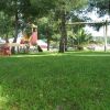 Prato con altalena e giochi sotto gli alberi.