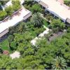 Vista dall'alto di edifici bianchi circondati da rigogliosi alberi e palme.
