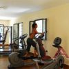 Due persone utilizzano attrezzi da palestra in una sala luminosa.