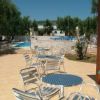 Tavoli e sedie in metallo su una terrazza con vista su una piscina e giardino.