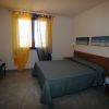 Camera da letto con letto matrimoniale, tende colorate e quadri sul muro.