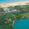 Vista aerea di un'area con laguna, piscine e vegetazione vicino alla spiaggia.