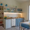 Cucina luminosa con frigorifero, mensole e tavolo, decorata in blu e bianco con un tocco marino.