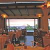 Ristorante con vista panoramica, tavoli apparecchiati e tramonto.