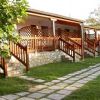 Una veranda di bungalow in legno, con scale e un vialetto in pietra davanti su un prato verde.
