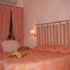 Una camera da letto con pareti rosa, letto matrimoniale con coperta arancione e fiori sul letto.