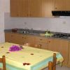 Cucina con tavolo coperto da tovaglia gialla, armadietti in legno chiaro e fornelli.