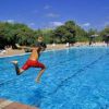 Persona in costume rosso mentre salta in una piscina azzurra.