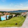 Un resort con prati, una piscina a sinistra e un edificio con torri a destra.
