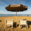 Due sedie a sdraio sotto un ombrellone sulla spiaggia.
