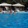 Piscina con ombrelloni bianchi, persone nuotano.
