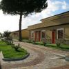 Viale pavimentato tra edifici bassi con tetti inclinati in un'area verde.