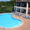 Piscina a forma libera con sedie a sdraio e ombrelloni a strisce.