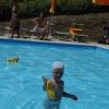 Bambino in piscina con cuffia e giocattolo giallo.