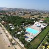 Vista aerea di un complesso con piscina vicino alla spiaggia e aree verdi.