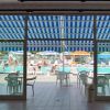 Piscina vista dall'interno, con sedie e ombrelloni colorati all'esterno.