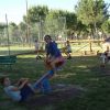 Bambini giocano su altalene a molla in un parco.