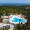 Piscina con scivolo circondata da verde e mare in lontananza.