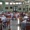 Ristorante ampio con sedie in legno e tovaglie bianche.