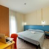Camera da letto con scrivania, laptop e letto matrimoniale.