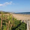 Una spiaggia sabbiosa con un percorso pedonale in legno e il mare sullo sfondo.