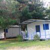 Due bungalow bianchi con porte e finestre blu, immersi tra gli alberi.