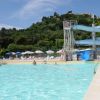 Piscina all'aperto con uno scivolo curvo, circondata da colline verdi.