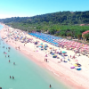 Spiaggia affollata con ombrelloni colorati e persone in mare.