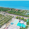 Vista aerea di un villaggio turistico con piscine e accesso alla spiaggia.