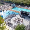 Piscina esterna affollata con scivoli, ombrelloni e un anfiteatro per attività.