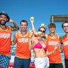 Un gruppo di persone in costume sulla spiaggia indossa magliette arancioni.