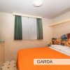 Letto matrimoniale con copriletto arancione in una stanza con finestra e armadietto.