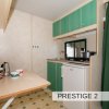 Interno cucina essenziale con mobili verdi, frigorifero e tavolo.