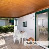 Veranda esterna con tetto in legno, tavolo apparecchiato e sedie bianche.