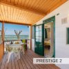 Terrazza in legno con vista mare, tavolo e sedie di plastica.