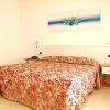 Letto matrimoniale con copriletto a motivi rossi.