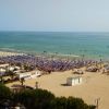 Spiaggia affollata con ombrelloni colorati vicino al mare.