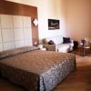 Camera con letto matrimoniale, testiera imbottita, divano bianco, tavolino e parete con quadro.