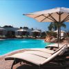 Lettini con ombrelloni accanto a una piscina azzurra all'aperto.
